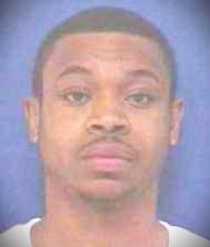 The image shows Andre in a white t-shirt. He has a mustache.