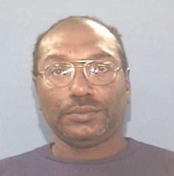 The photo shows Grayson in a dark t-shirt with glasses. Grayson, who is African American, is partially bald. He also has a mustache.