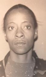 The black and white photo shows an African American woman with her hair pulled back. She has a t-shirt and button down shirt on.