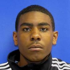 The image shows Tyran in a black and white stripped shirt. He is not smiling.